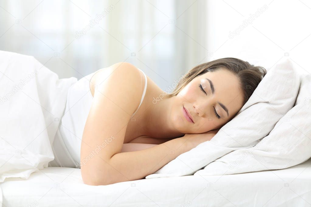Relaxed woman sleeping on a bed at home in the morning with daylight