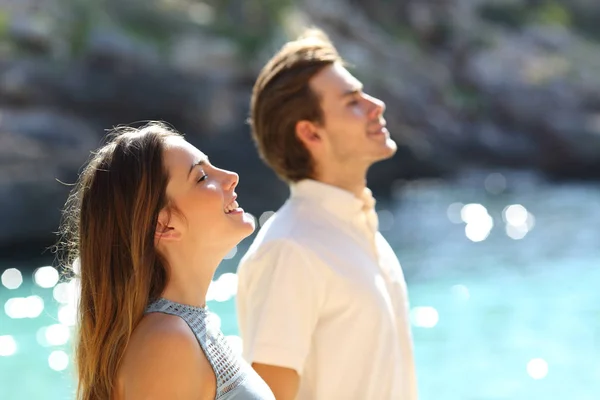 侧面视图的一对幸福夫妇呼吸新鲜空气在海滩上度假 — 图库照片
