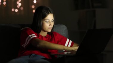 Gece evde bir kanepede oturan bir dizüstü bilgisayar yazmaya ciddi teen