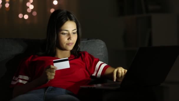 愉快的青少年在线支付信用卡在晚上坐在沙发上在家 — 图库视频影像
