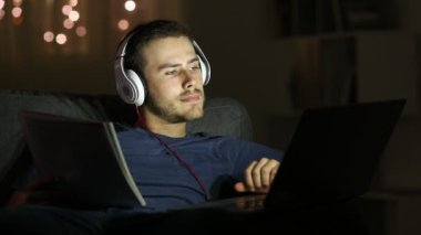 Çalışkan öğrenci e-öğrenme karşılaştırma notları gece evde bir kanepede oturan bir dizüstü bilgisayar ile