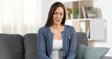 Evde bir kanepede sittin bel ağrısı acı bir kadın portresi önden görünüm