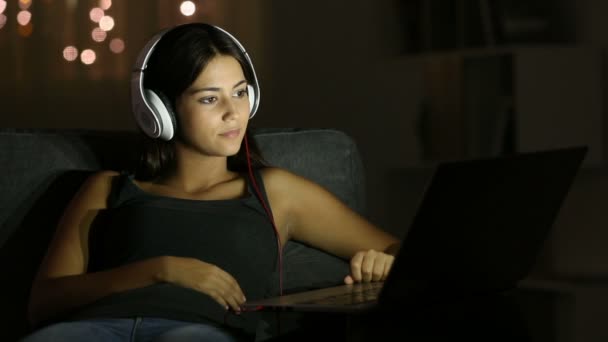 Boldog Lány Használ Egy Laptop Fejhallgató Egy Kanapén Otthon Éjszaka — Stock videók