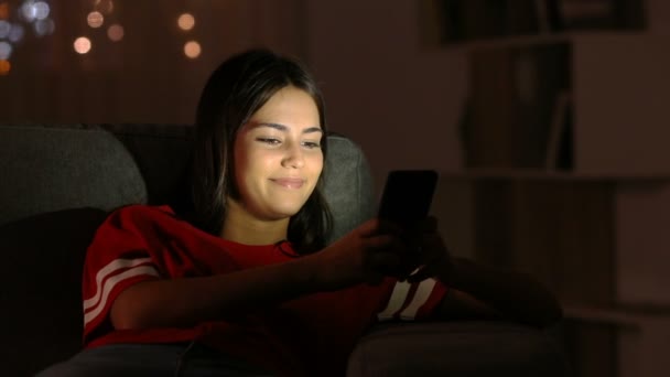 Feliz Adolescente Conversando Com Telefone Inteligente Sentado Sofá Casa Noite — Vídeo de Stock