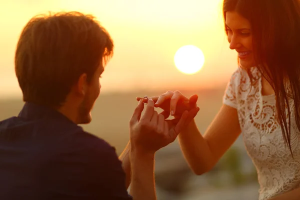 愉快的人把订婚戒指在女友手指在日落海滩上 — 图库照片