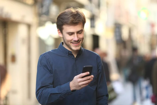 笑脸人检查智能手机内容走在老城区的街道上 — 图库照片