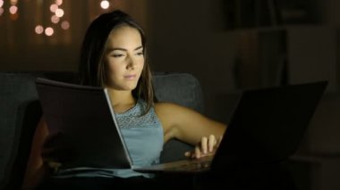 Öğrenci e-öğrenme karşılaştırma kağıt notları gece evde bir kanepede oturan bir dizüstü bilgisayar ile