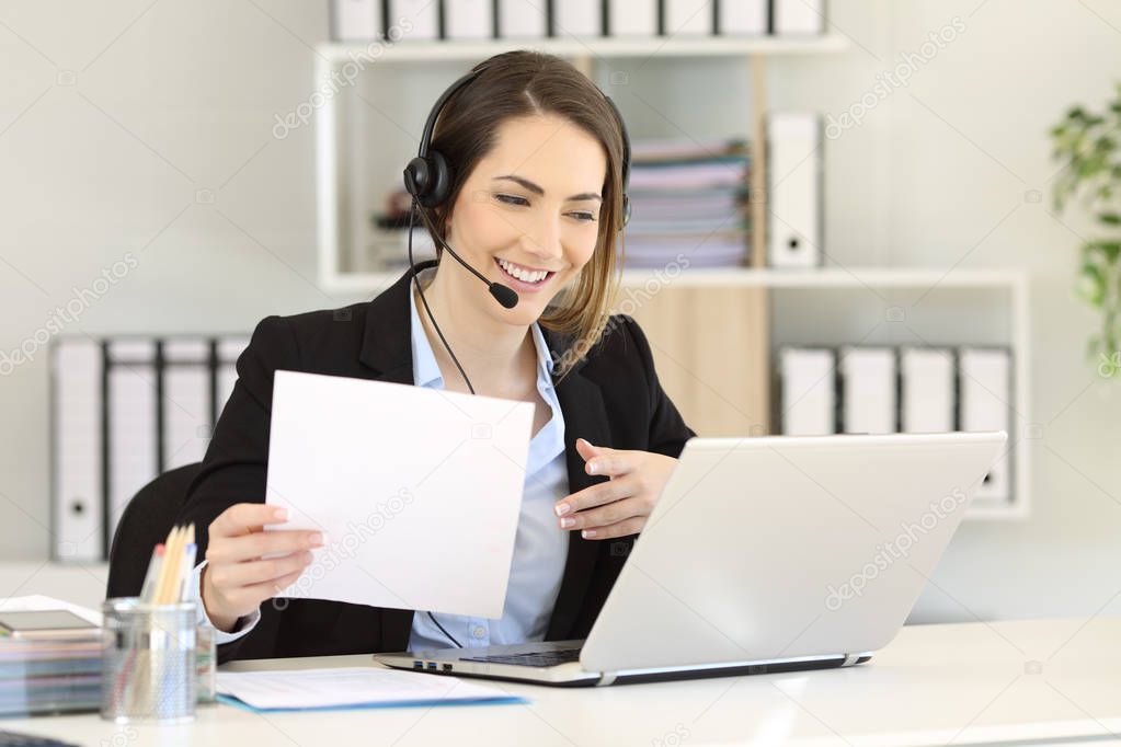 Telemarketer attending a call consulting online information in a laptop at office