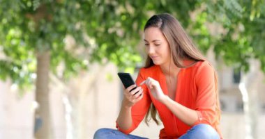 İyi haber bir parkta bir bankta oturmuş bulma bir akıllı telefon kullanan heyecanlı kadın