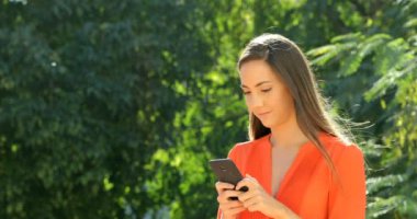 Mutlu kadın yürüyüş ve bir parkta telefonda konuşurken turuncu