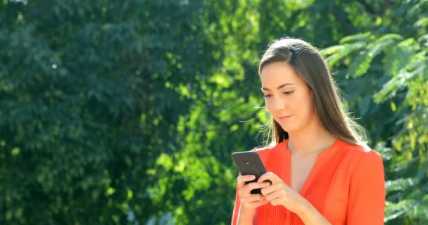 Mulher Feliz Andando Usando Telefone Inteligente Para Conversar Parque — Vídeo de Stock