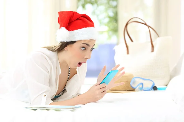 Возбужденная Женщина Смотрит Рождественский Телефон Лежащий Кровати Гостиничном Номере — стоковое фото