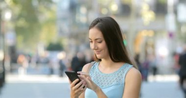 Heyecanlı kadın sokakta bir akıllı telefon online iyi haber okuma