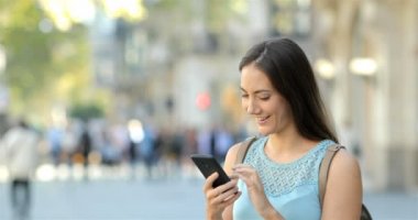 Mutlu kadın sokakta akıllı telefon içeriğini görüntülemek