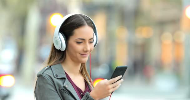 Chica Sonriente Con Auriculares Escuchando Música Desde Teléfono Inteligente Calle — Vídeo de stock