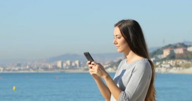 Sahilde bir akıllı telefon üzerinde ciddi kadın manifatura yan görünümü portresi