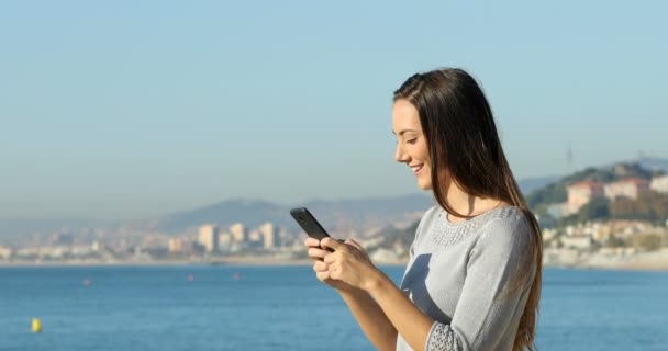 電話で浜に立って上幸せな女のテキスト メッセージのプロファイル — ストック動画
