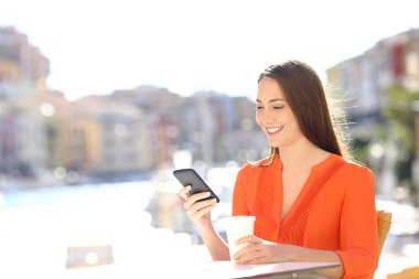 Mutlu kadın bir akıllı telefon bir sahil kasabası bir kahve dükkanında tatile kullanır