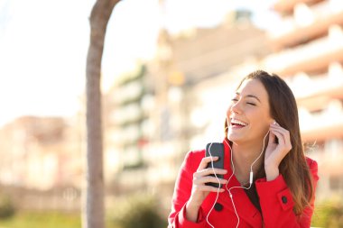 Şarkı ve müzik bir parkta bir bankta oturmuş bir smartphone--dan mutlu kadın
