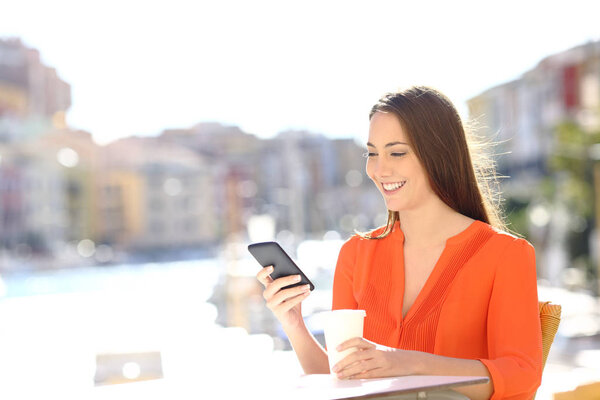 Счастливая дама пользуется смартфоном в кафе прибрежного городка на отдыхе
