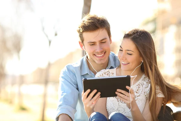 幸福的夫妇分享在线平板电脑内容坐在公园的长凳上 — 图库照片