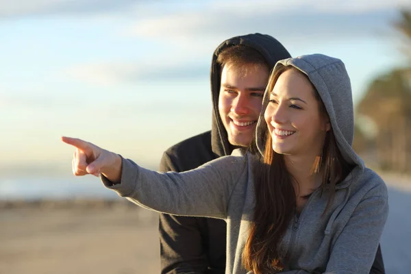 サンライズ ビーチで水平線を指差し幸せな十代の若者たちのカップル — ストック写真