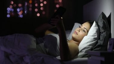 Sürpriz teen gece evde bir yatakta yatarken bir akıllı telefon olarak iyi haber okuma