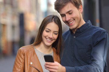 Akıllı telefon içeriği sokakta izlerken mutlu bir çift önden görünümü