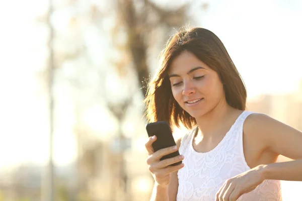 女性が公園のベンチに座っているスマート フォンを使用して — ストック写真