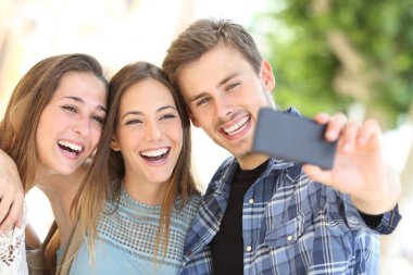 Selfies bir akıllı telefon ile birlikte sokakta alarak üç mutlu arkadaş portresi