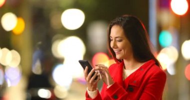 Heyecanlı kadın gece sokakta bir akıllı telefon üzerinde iyi haber denetleme