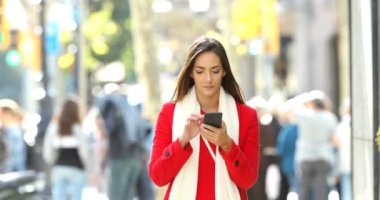 İyi haber online bir akıllı telefon üzerinde sokakta kışın alma kameraya doğru yürüyen bir heyecan kadın önden görünümü