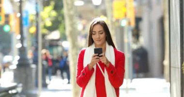 Mutlu bir kadın kamera, mesaj doğru sokak akıllı telefon kışın yürürken önden görünümü