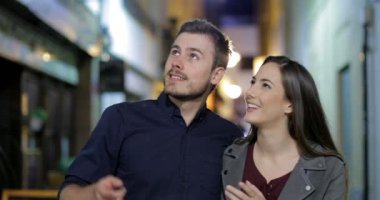 Mutlu bir çift kamera gezi gece sokakta doğru yürüyüş önden görünümü