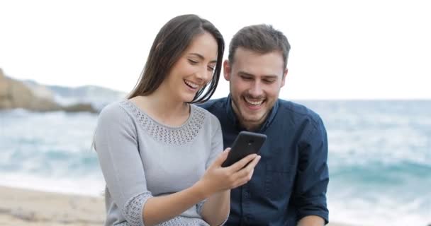 Heureux Couple Naviguant Sur Contenu Téléphone Intelligent Sur Plage — Video