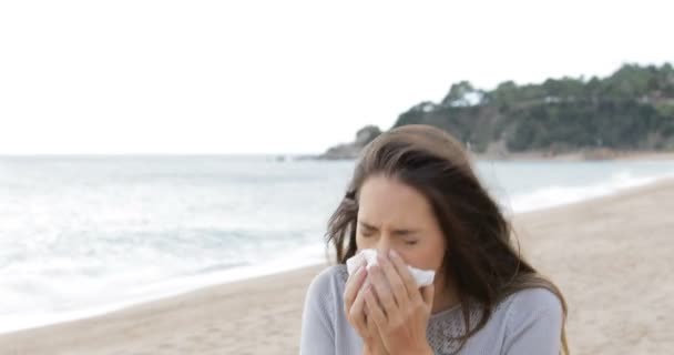 ビーチの上を歩くティッシュで覆って口をくしゃみアレルギーの女性 — ストック動画