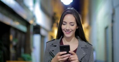 Akıllı telefon gece sokakta yürüyen mutlu kadın ve manifatura önden görünüm