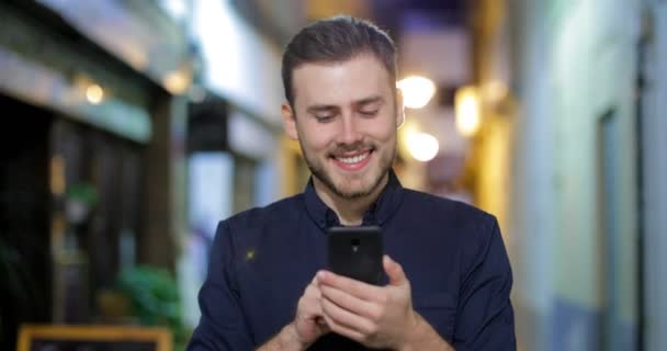 Vista Frontal Homem Feliz Caminhando Direção Câmera Usando Telefone Inteligente — Vídeo de Stock