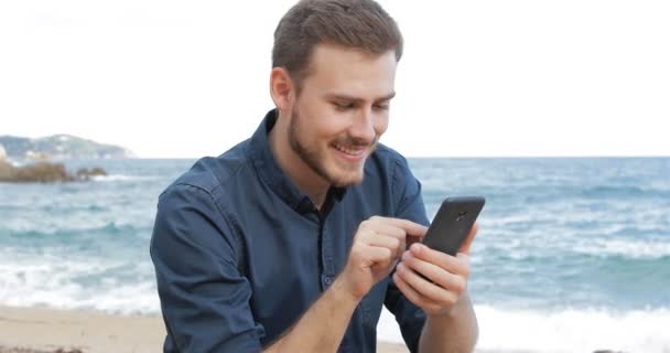 Homem Feliz Navegando Conteúdo Telefone Inteligente Sentado Praia — Vídeo de Stock