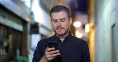 Gece sokakta akıllı telefon içeriğini görüntülemek kameraya doğru ciddi bir adam portresi önden görünüm