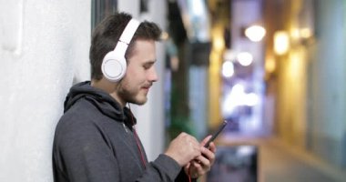 Mutlu genç çocuk sokakta bir duvara yaslanmış gece müzik