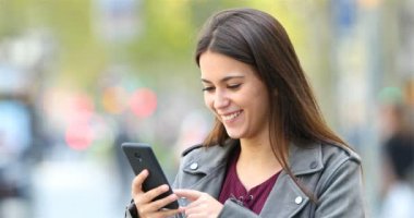 Mutlu genç çizgi akıllı telefon içerik ile yeşil bir arka sokakta üzerinde tarama