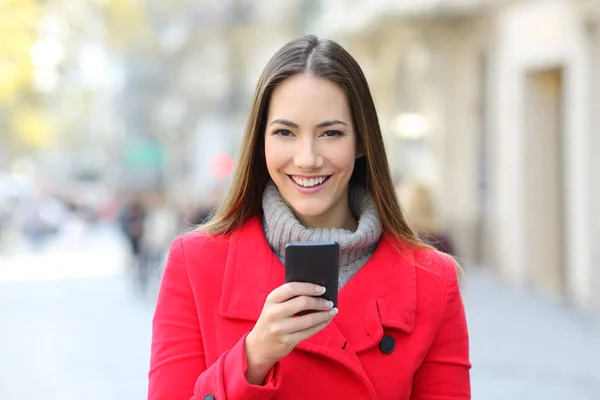 通りで赤で幸せな女性の正面肖像画を見てスマート携帯電話を保持します — ストック写真