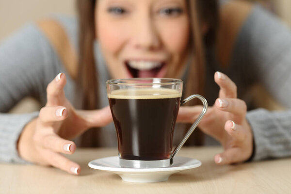 Front view close up of an amazed woman looking at a coffee cup with crave