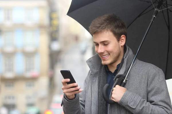Щасливий Чоловік Перевіряє Смартфон Під Парасолькою Взимку Вулиці — стокове фото