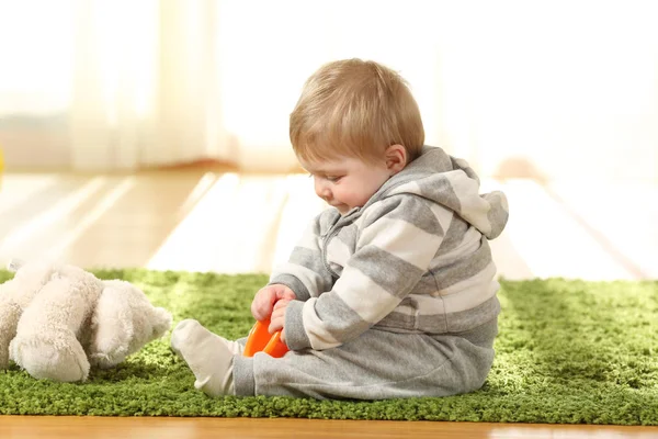 宝宝一个人在家里的地毯上玩玩具 — 图库照片