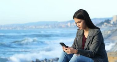 Akıllı telefon kontrol ve ufuk plaj bakarak rahat teen