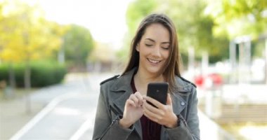 Mutlu bir kadın yürüyüş ve bir parkta akıllı telefon üzerinde tarama önden görünümü