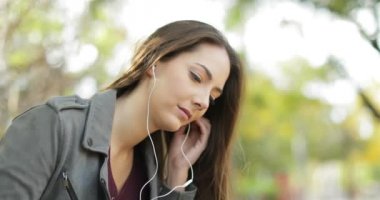 Kulaklıkları kulaklara koyarak ve bir parkta bir akıllı telefondan müzik dinlerken rahat kadın