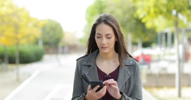 Vooraanzicht Van Een Perplex Vrouw Lopen Controleren Slimme Telefoon Inhoud — Stockvideo